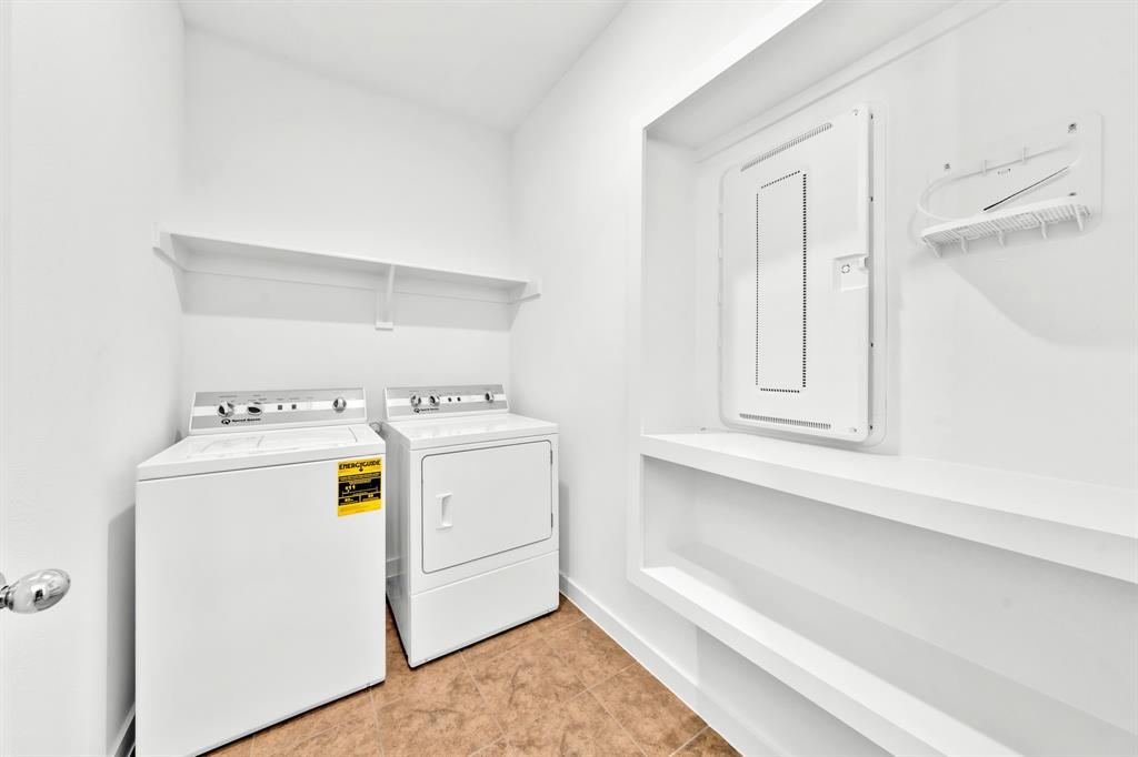Laundry area with a top-load washer, front-load dryer, and two wall-mounted shelves