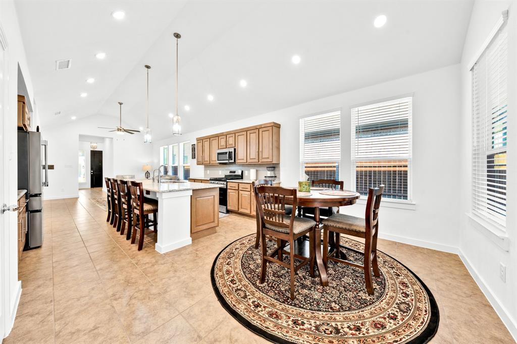 Vaulted ceiling kitchen featuring recessed lighting, a center island with bar seating, wood cabinetry, and tile flooring