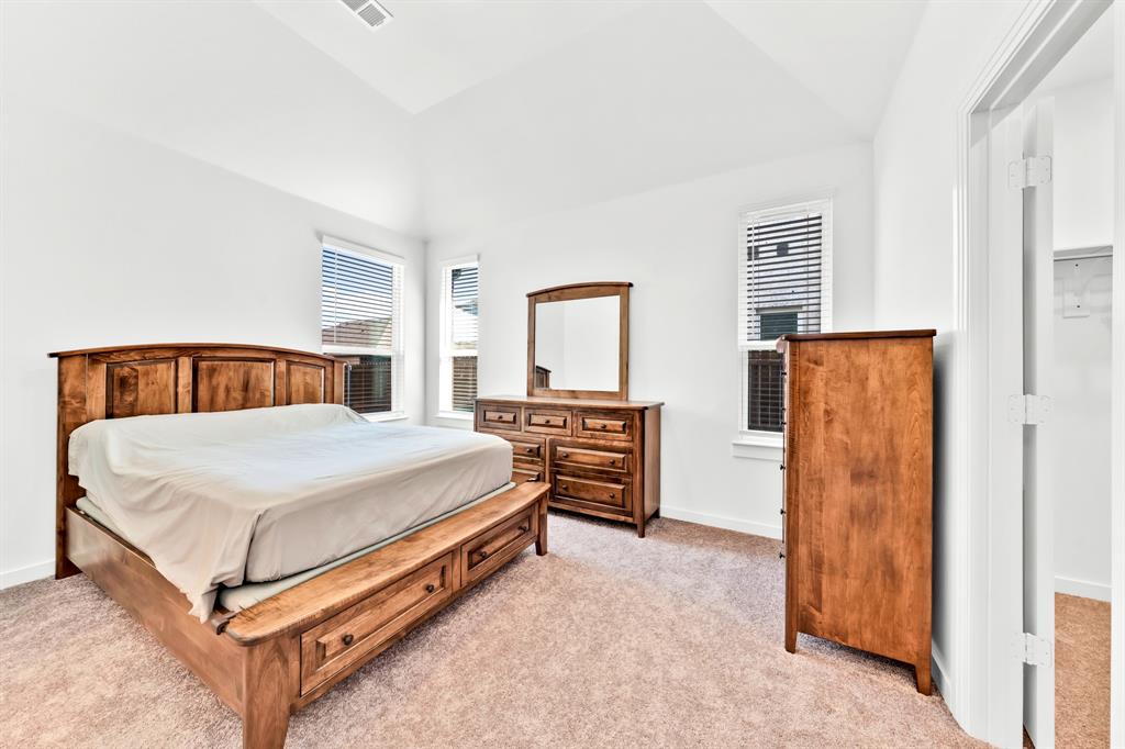 Vaulted ceiling, two windows with blinds, light-toned carpeting, and white walls