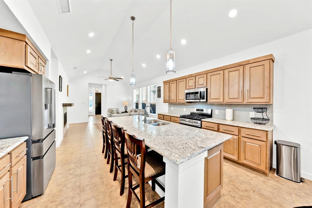 Kitchen featuring light-tone cabinetry, stainless steel appliances, a large center island with a sink, and pendant lighting