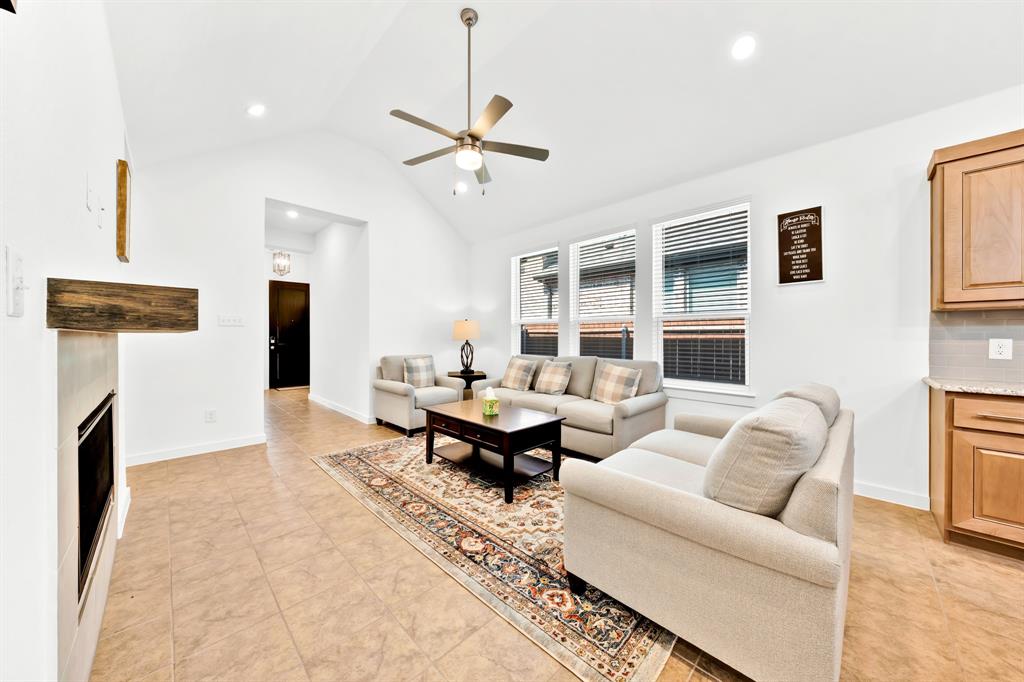 Vaulted ceiling with a ceiling fan, recessed lighting, tile flooring, built-in fireplace, and kitchen cabinetry with a countertop