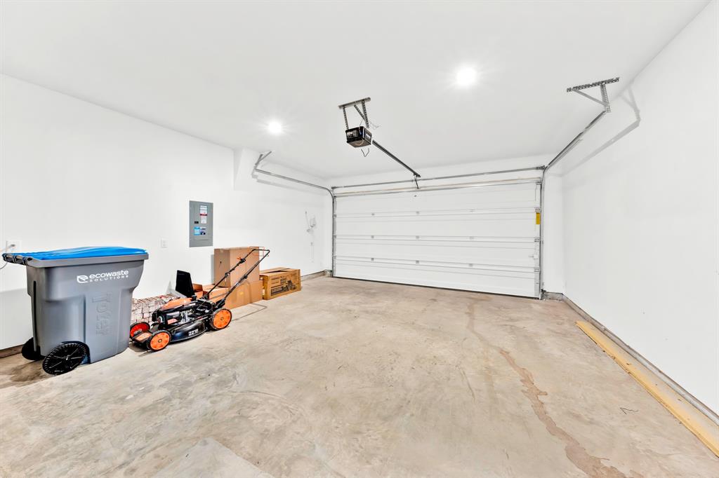 Spacious garage with a concrete floor, white walls, and a white overhead door
