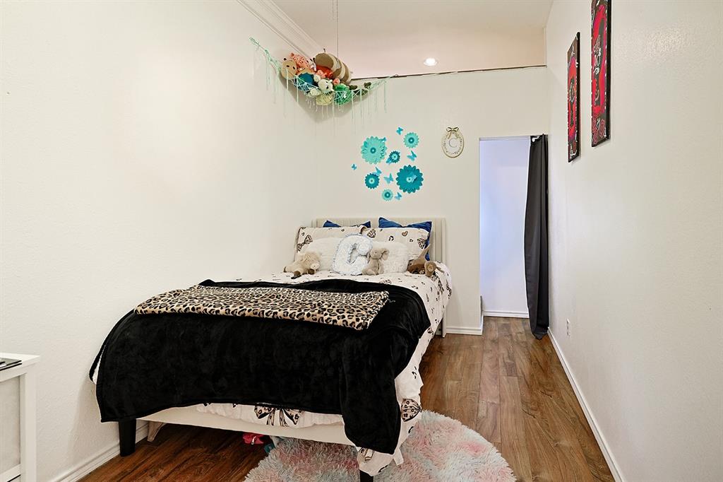 Room featuring wood-finish flooring, smooth white walls, and crown molding