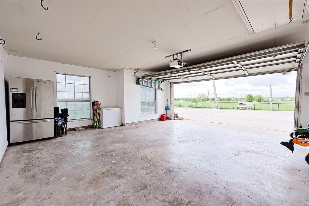 Attached two-car garage with concrete flooring, motorized sectional garage door, multiple grid-pane windows, and high ceilings