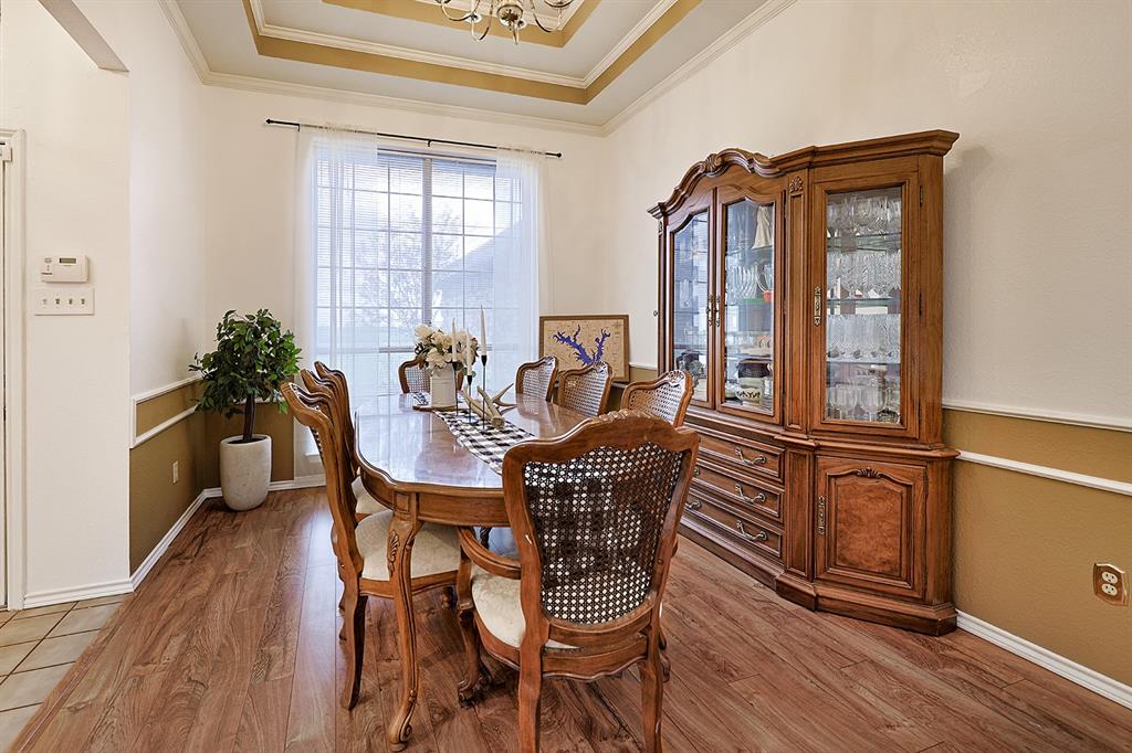 Dining area featuring wood-finish flooring, tray ceiling, decorative wall molding, and a large window