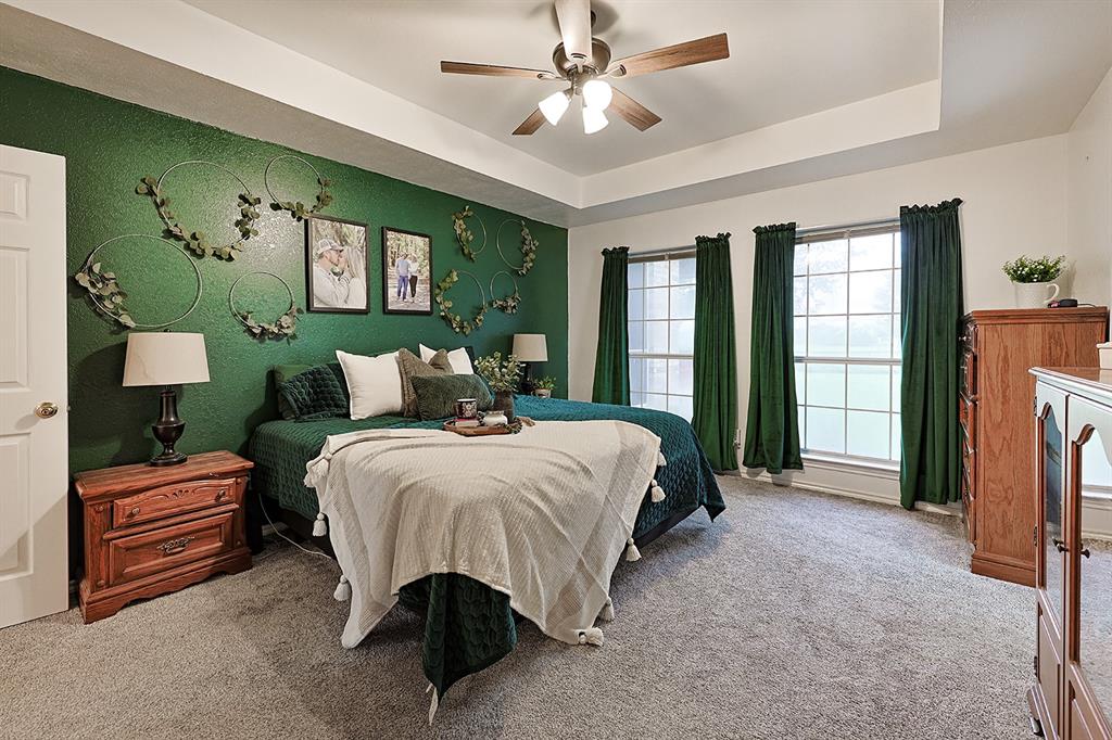 Tray ceiling featuring a central multi-blade ceiling fan with integrated lighting and multi-pane windows