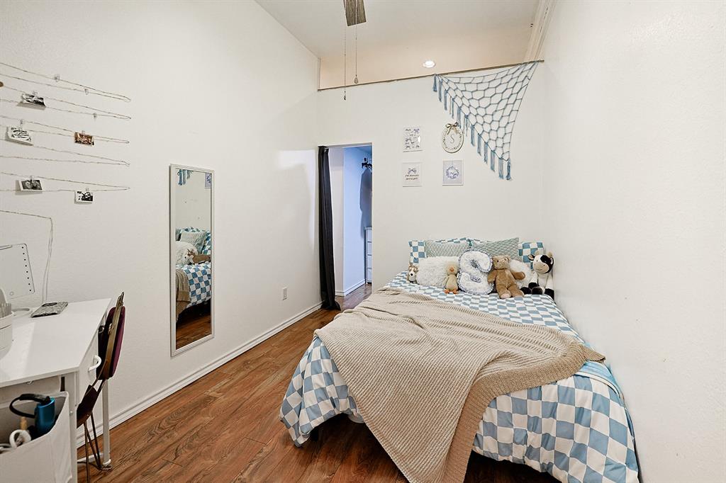 Vaulted ceilings, wood-finish flooring, and wall-mounted full-length mirror