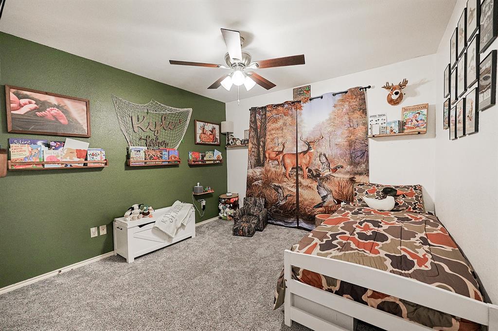 Bedroom featuring wall-to-wall carpeting, ceiling fan with integrated lighting, and built-in wooden shelving