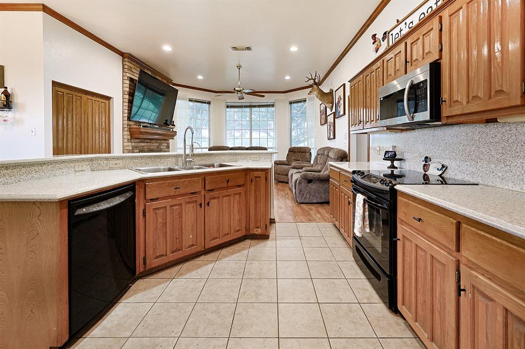 Kitchen featuring wood cabinetry, stone-finish countertops, tile flooring, recessed lighting, and a brick fireplace