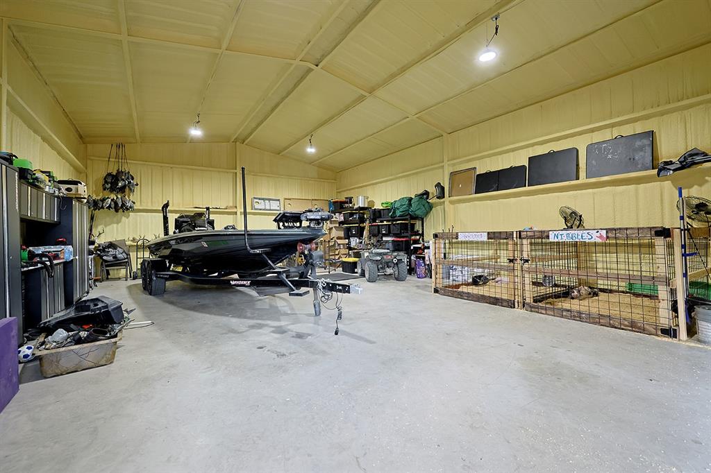 Expansive metal workshop featuring high-clearance ceilings, concrete flooring, integrated overhead lighting, and built-in wall shelving