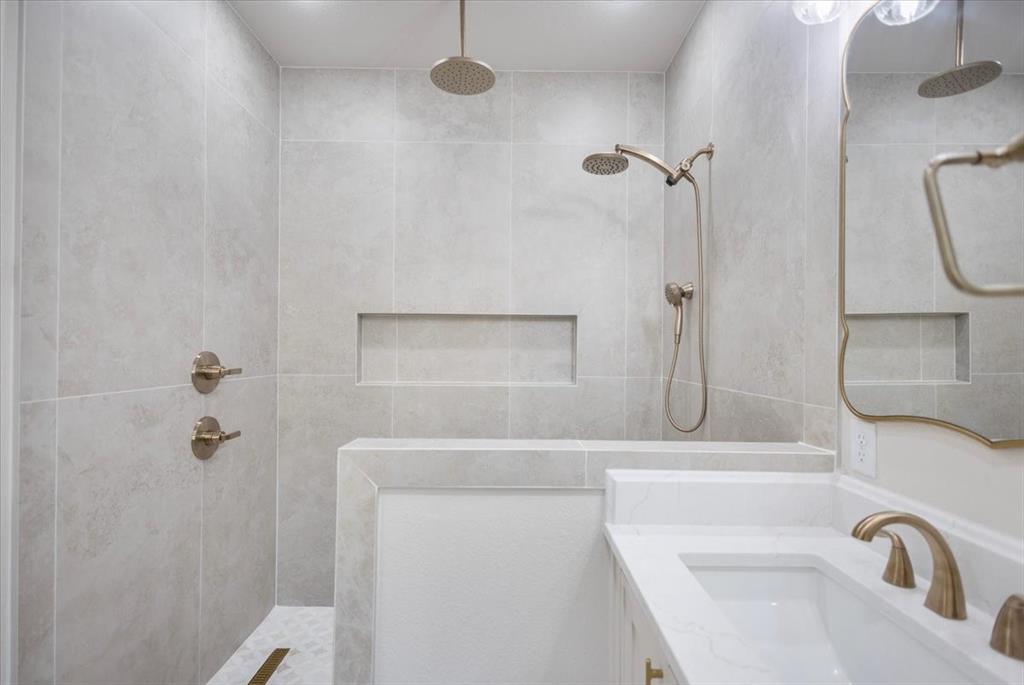 Walk-in shower with light-toned wall tile, built-in shower bench, and recessed shower niches
