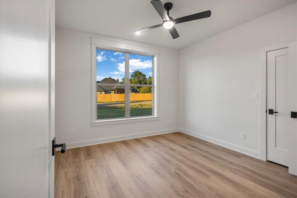 Light-filled room featuring wood-finish flooring and a ceiling fan