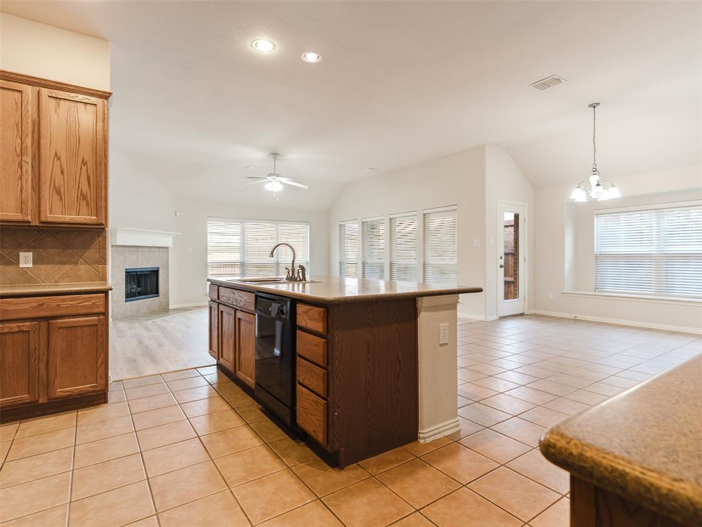 Kitchen island with countertop seating, wood cabinetry, tile flooring, built-in fireplace, and recessed lighting