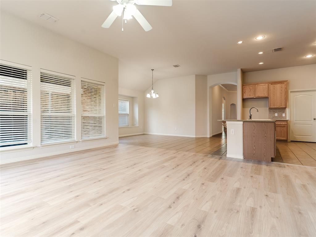 Open-concept living space featuring wood-finish flooring, a vaulted ceiling, recessed lighting, and a kitchen peninsula with cabinetry
