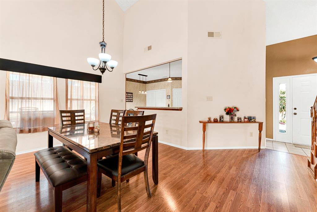 Tall, dramatic wall volumes meet glowing pendant lighting to define a sophisticated, intimate dining zone near the home's entry. You can easily envision lingering over evening wine and dessert as warm light fills the surrounding open space.