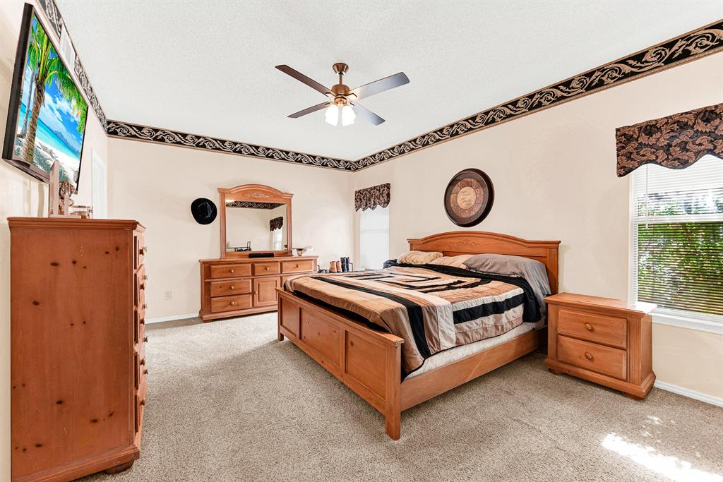 Dual aspect windows illuminate plush carpeted floors, creating a bright and generous layout anchored by a classic ceiling fan. It offers a serene haven for curling up with your favorite book as afternoon sun streams through the blinds.