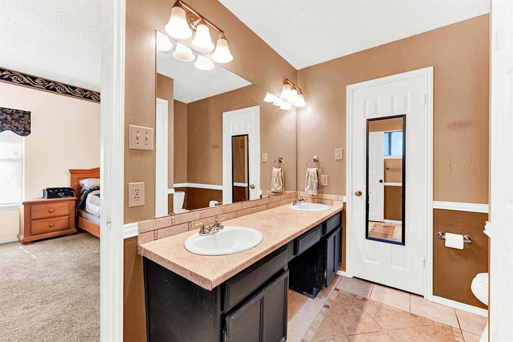 A spacious vanity area with double sinks and vanity lights provides optimal space and function. Morning routines become smooth and enjoyable as two people comfortably prepare for the day side-by-side.