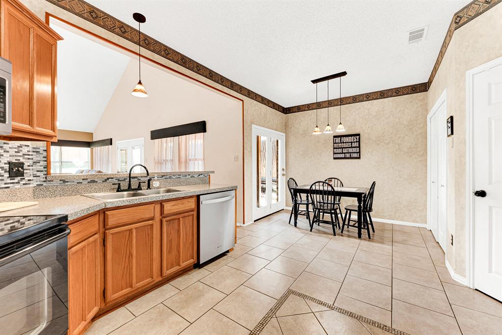 Expansive tile flooring connects the prep space to the dining alcove in one continuous, open layout. This seamless flow makes setting the table and serving fresh home-cooked meals feel completely effortless