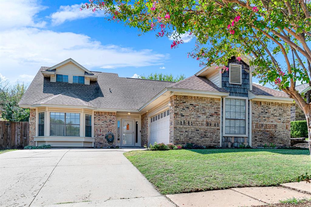 A mature flowering crape myrtle frames the manicured lawn and multi-textured exterior walls. It sets the scene for welcoming neighbors or stepping out on a breezy afternoon to enjoy the curb appeal.