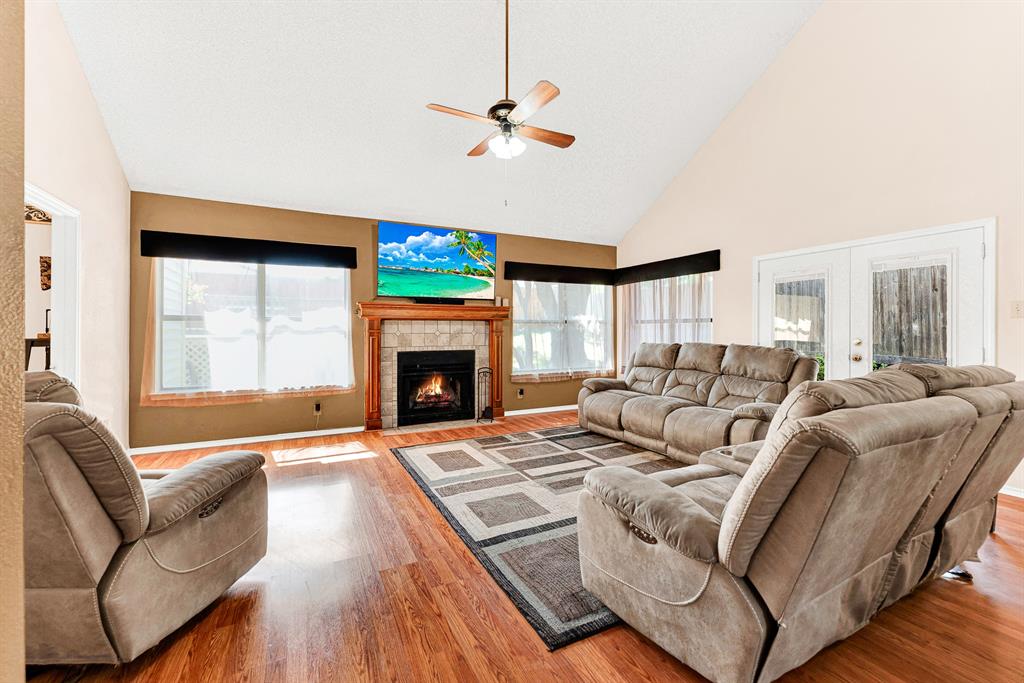 Expansive double-hung windows framed by soft window treatments draw gentle daytime sunlight across rich wood-toned flooring. It creates an idyllic setting for sipping your morning coffee while watching sunlight drift across the room.