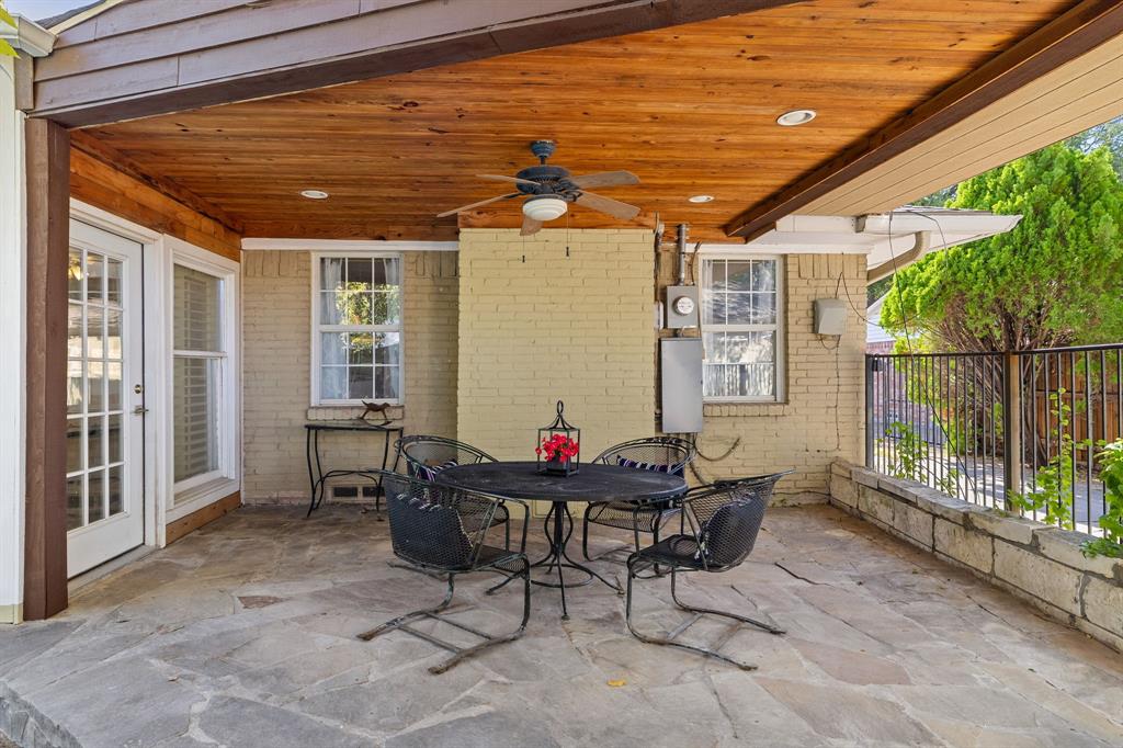 This covered patio is an amazing place to relax or entertain!  It features a natural stone floor, wood-plank ceiling, recessed lighting, and a painted brick exterior wall.
