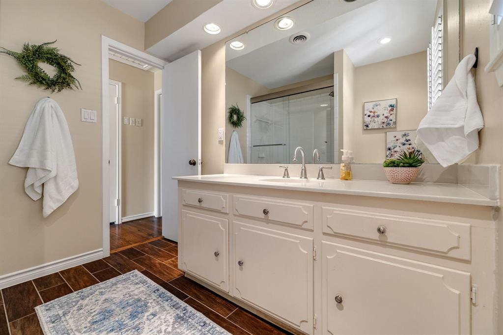Another view of the guest bathroom showing the large vanity, reccessed lighting and wood like ceramic tile.