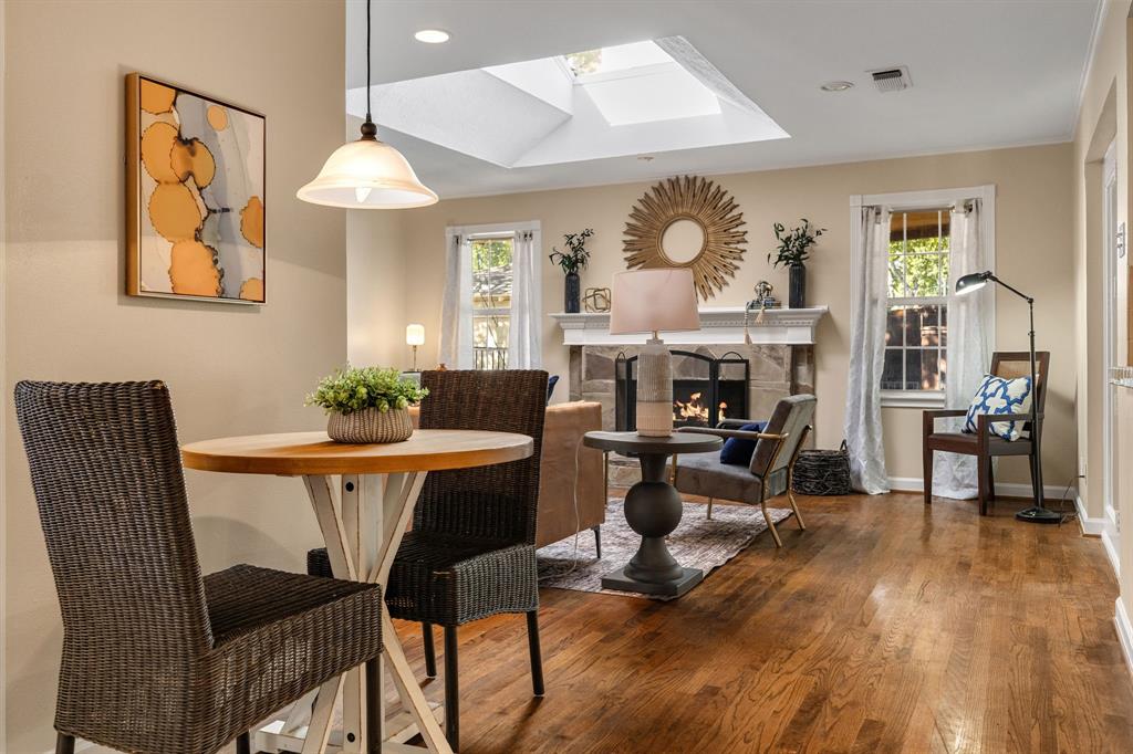 Wood-finish flooring, stone-surround fireplace with a detailed mantel, skylight, and pendant lighting