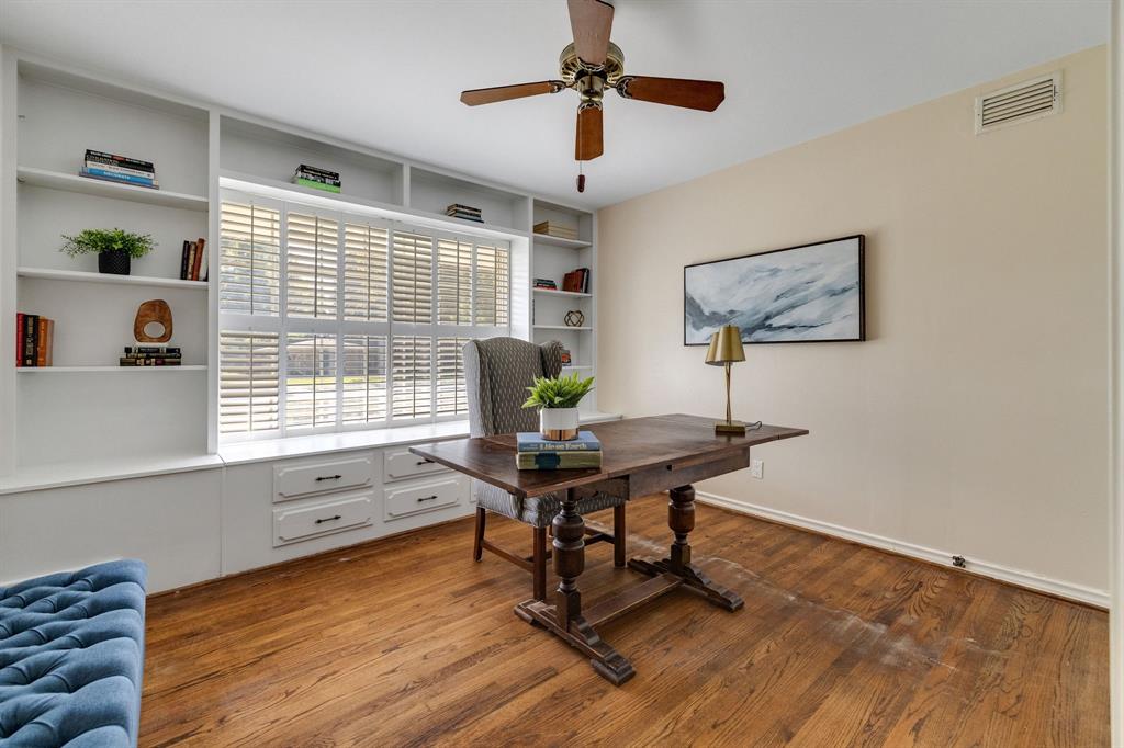 This is the second of two secondary bedrooms.  This room features the continued wood floors and an amazing wall of built-in floor-to-ceiling shelving, custom window seat with lower storage drawer, and large window with plantation shutters.  This room has also been freshly painted.