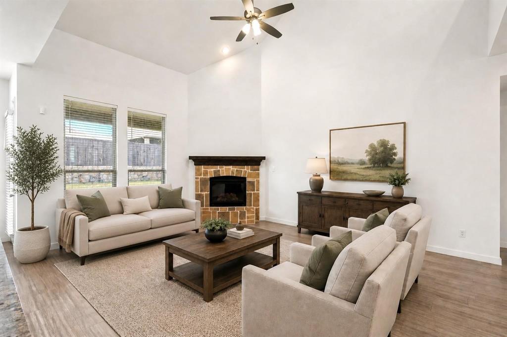 Vaulted ceilings, stone-surround fireplace with a dark wood mantle, wood-finish flooring, and large windows Vaulted ceilings, stone-surround fireplace with a dark wood mantle, wood-finish flooring, and large windows