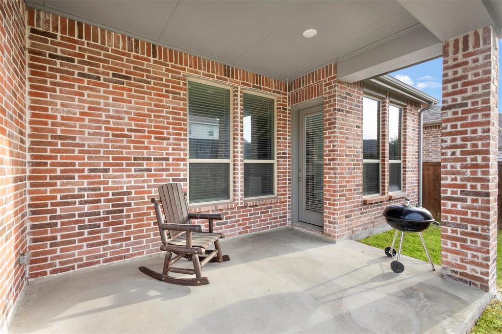 Covered patio featuring red brick exterior walls, a concrete floor, recessed ceiling lighting, and multiple windows