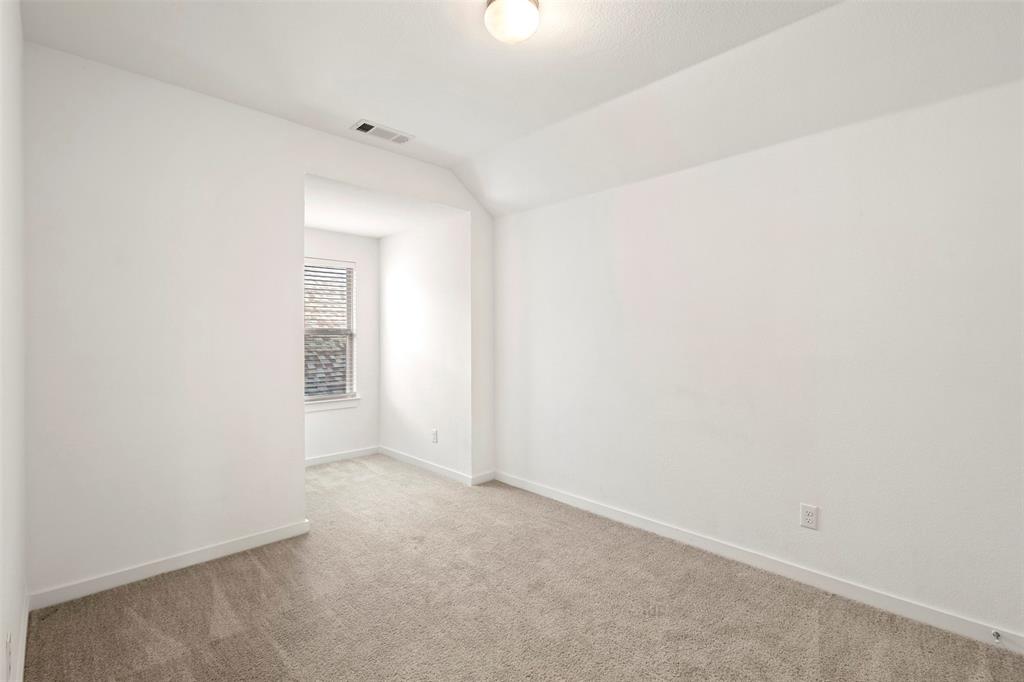 Interior room featuring neutral wall-to-wall carpeting, vaulted ceilings, and a recessed window nook with a single-pane window