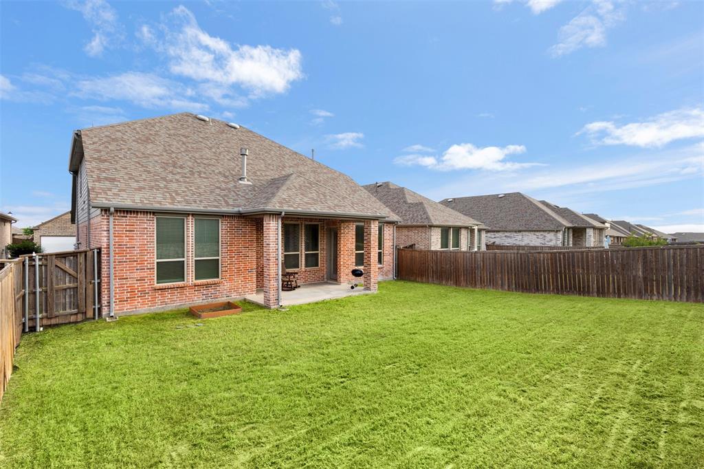 Rear exterior featuring red brick masonry, a covered concrete patio, a private fenced yard, and a shingled roof