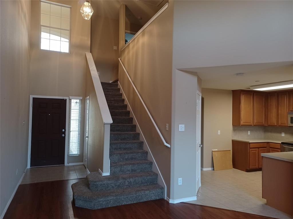 Two-story foyer with wood-finish flooring, a carpeted staircase, and a decorative pendant light fixture