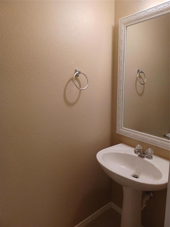 Pedestal sink with dual-handle faucet, framed wall mirror, and wall-mounted towel ring
