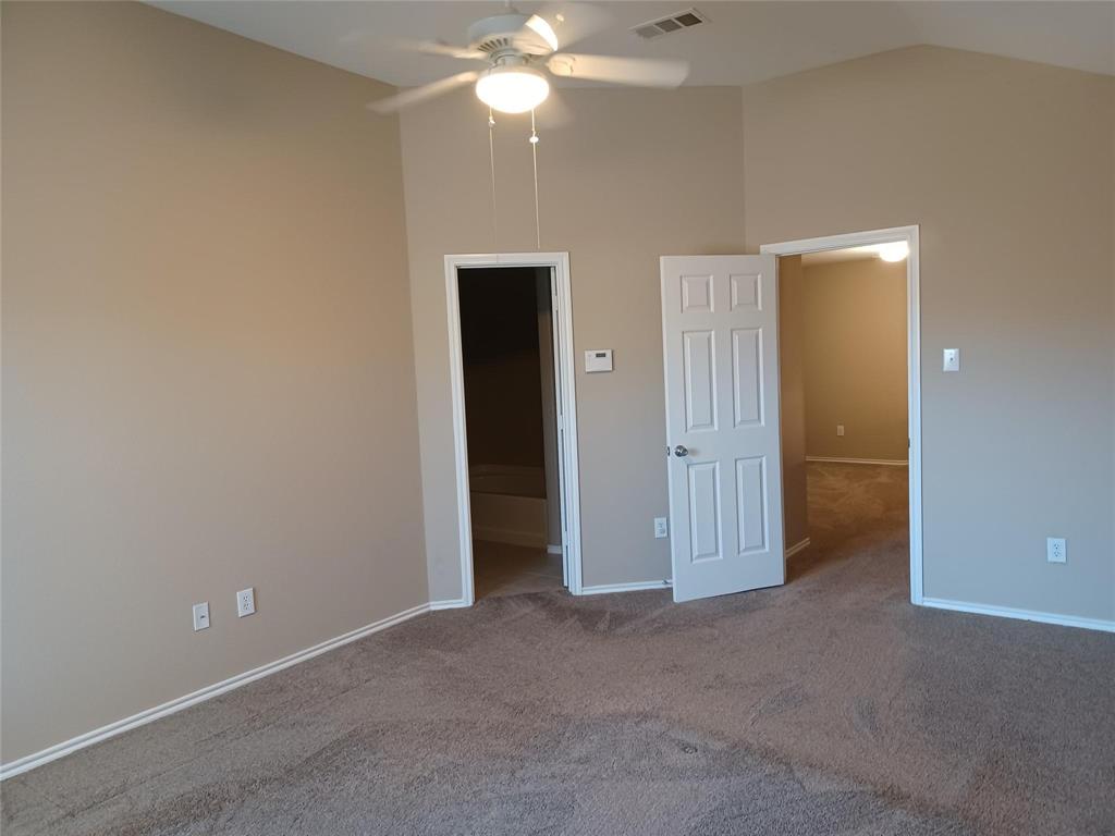 Vaulted ceiling, ceiling fan, neutral carpet, paneled interior doors, light-toned wall paint