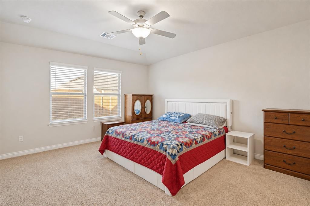 Neutral-toned room featuring high ceilings, wall-to-wall carpeting, a multi-blade ceiling fan with integrated lighting, and dual windows equipped with horizontal blinds