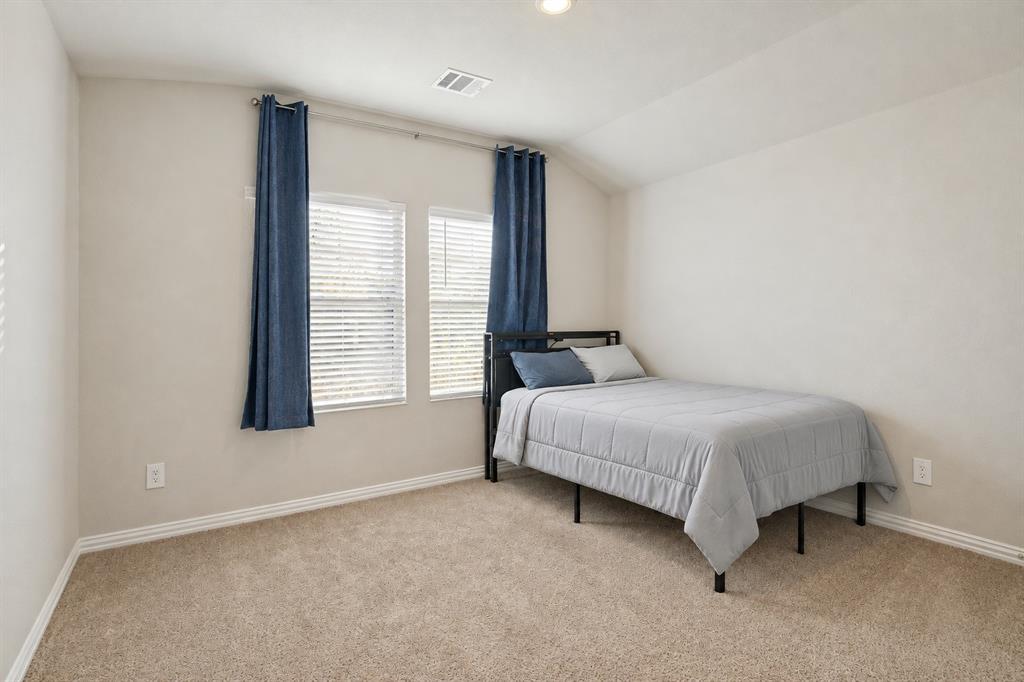 Neutral-toned bedroom featuring high-vaulted ceilings, wall-to-wall carpeting, and double-pane windows with integrated blinds