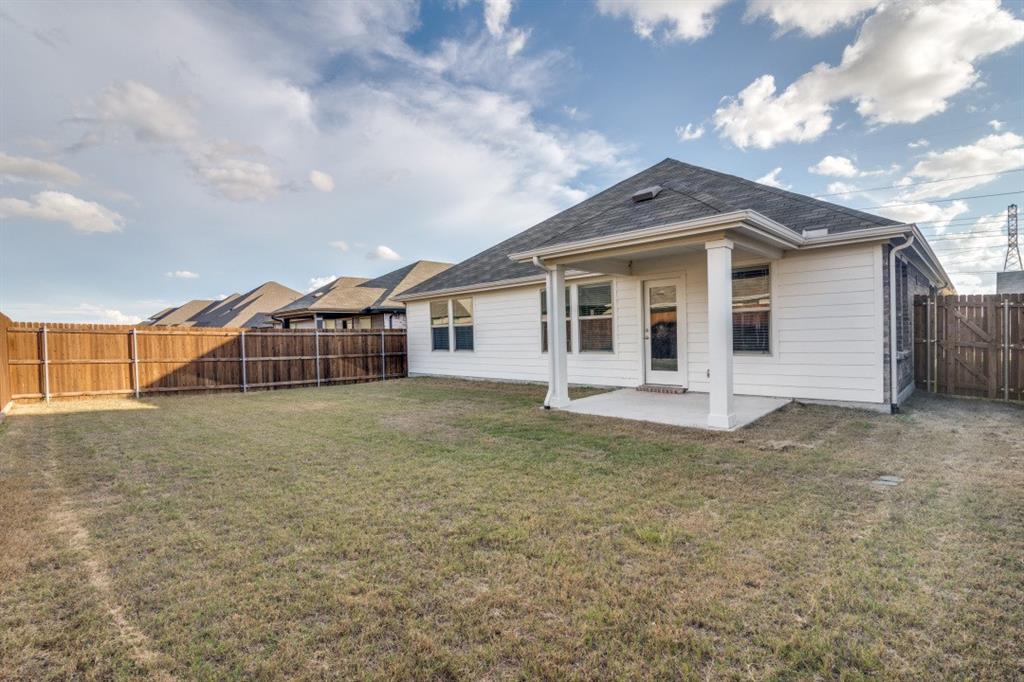 Rear exterior featuring horizontal lap siding, a covered patio with columns, and a perimeter wood fence