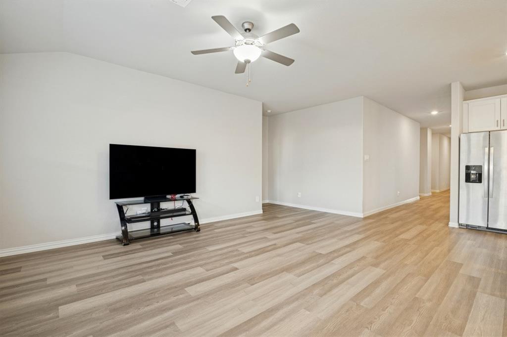 Wood-finish flooring, vaulted ceilings, and a ceiling fan with integrated lighting fixture
