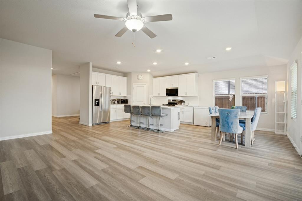 Open-concept kitchen featuring white cabinetry, a center island, stainless steel appliances, wood-finish flooring, and recessed ceiling lighting Open-concept kitchen featuring white cabinetry, a center island, stainless steel appliances, wood-finish flooring, and recessed ceiling lighting