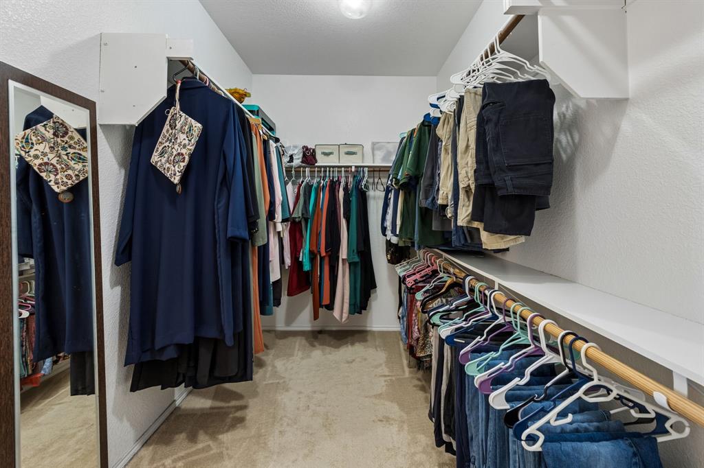 Walk-in closet featuring built-in shelving, multiple hanging rods, and a full-length mirror