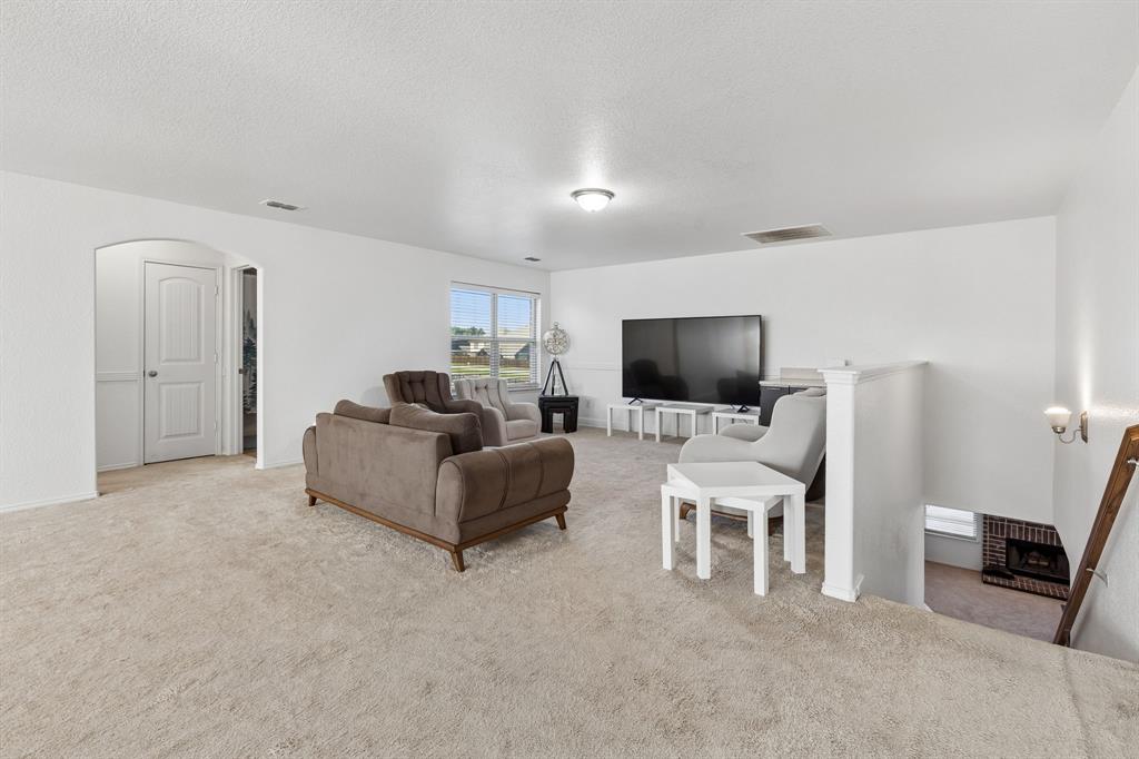 Carpeted living area with white walls, an arched doorway, and built-in lighting