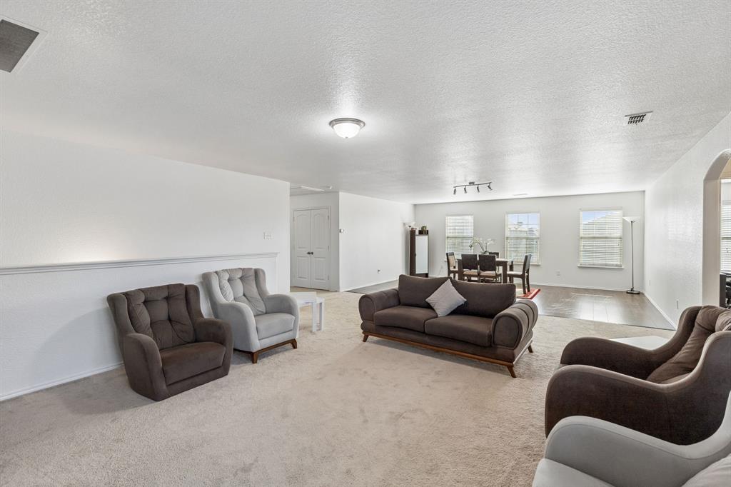 Expansive carpeted living area with a half wall detail and overhead lighting