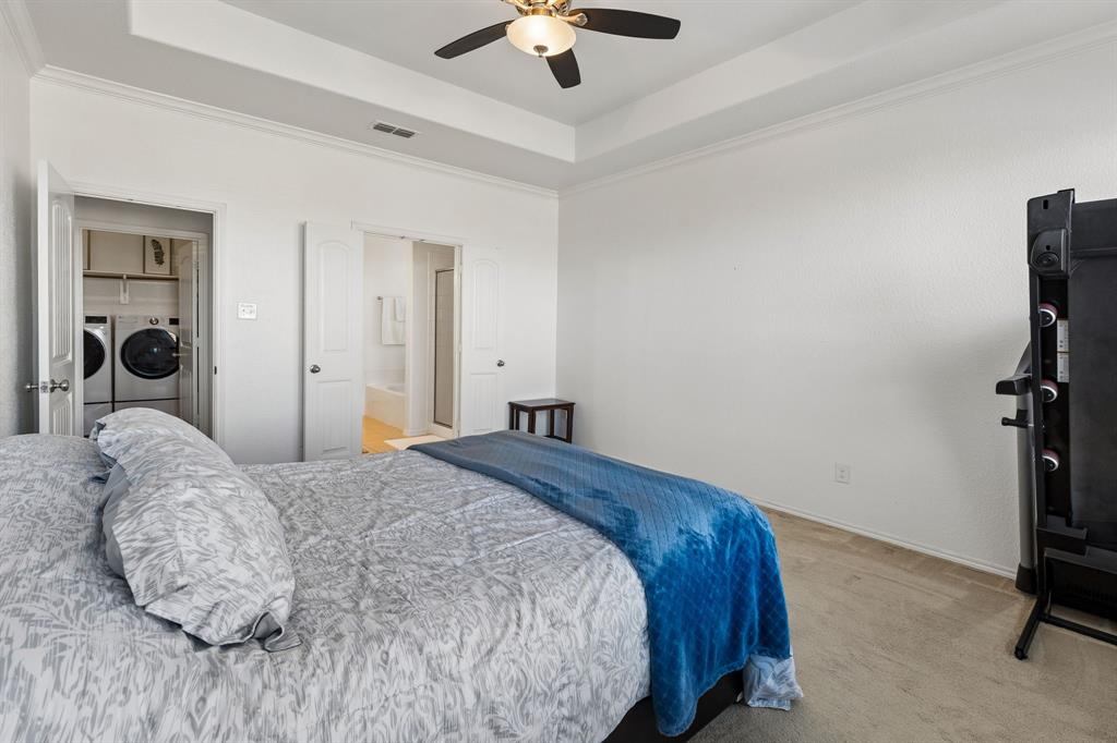 Tray ceiling with crown molding, ceiling fan, and wood-finish flooring