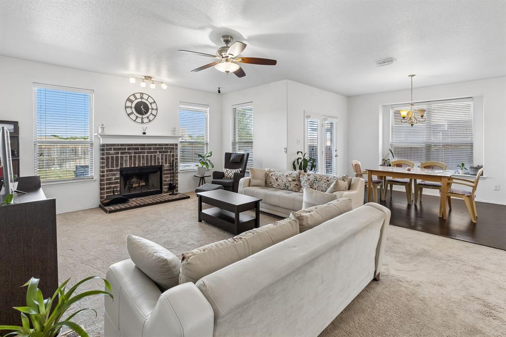 Living area with a brick fireplace, white mantel, and ceiling fan