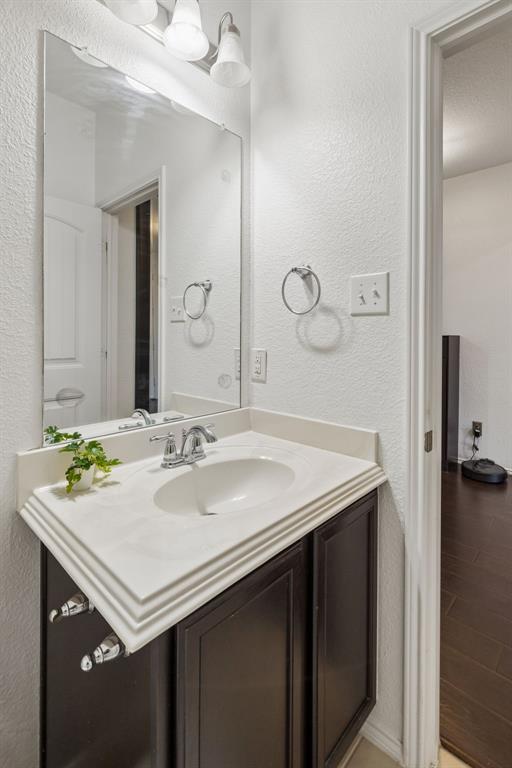 Vanity with a white countertop and integrated sink, chrome faucet, dark wood-finish cabinetry, and a large wall-mounted mirror