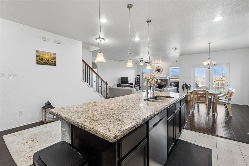 Kitchen island featuring a granite countertop, undermount sink, and stainless steel dishwasher
