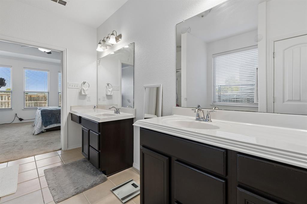 Dual vanities with integrated sinks, dark wood-finish cabinetry, and tiled flooring