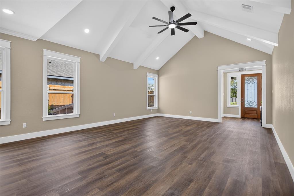 Vaulted ceilings with exposed beams, wood-finish flooring, recessed lighting, ceiling fan, and entry door with decorative glass insert