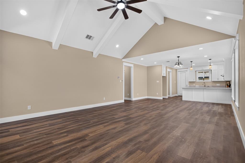 Vaulted ceilings with exposed beams, wood-finish flooring, recessed lighting, and kitchen cabinetry with integrated peninsula